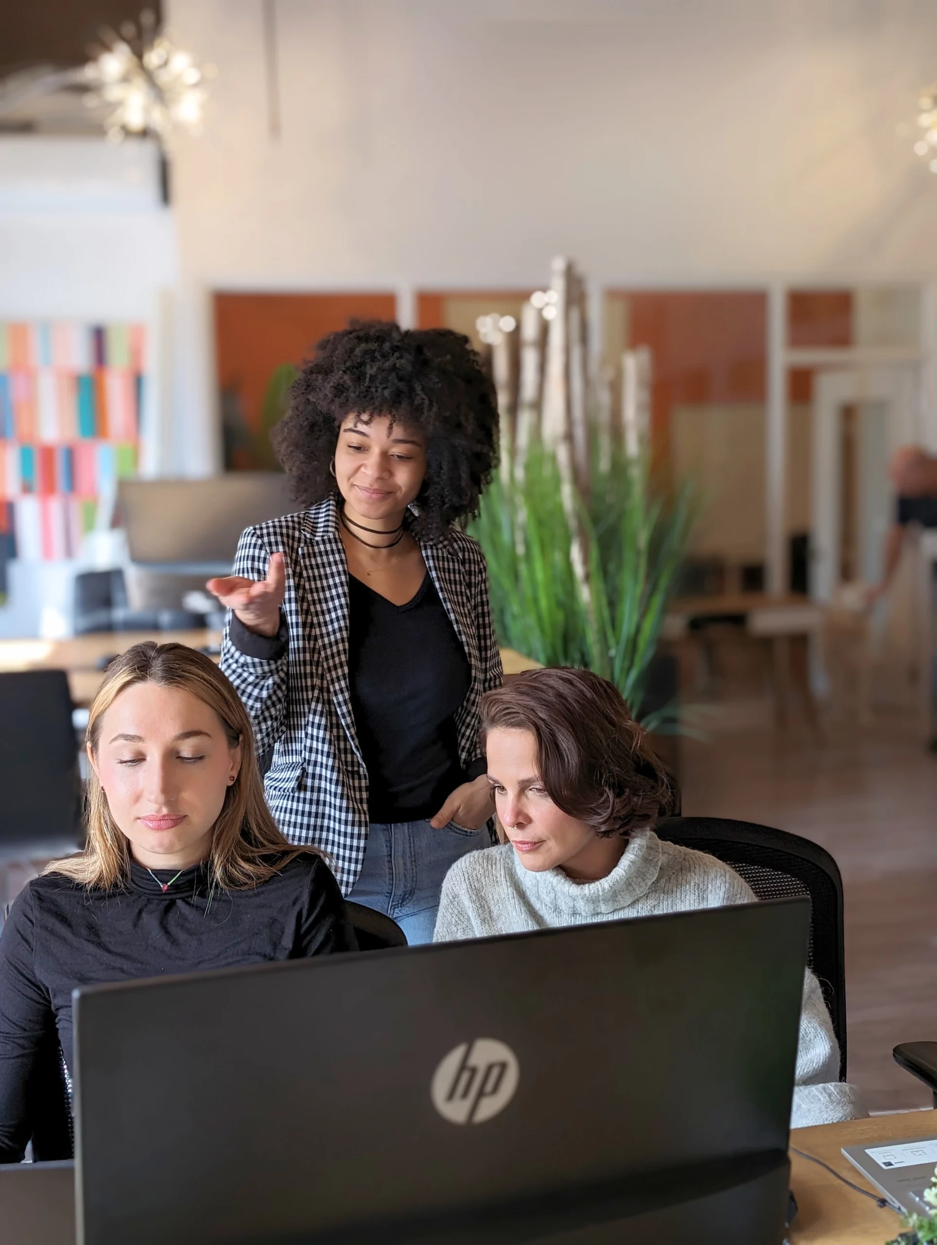 Trois femmes concentrées travaillant ensemble dans un open space d'une agence web Montréalaise.